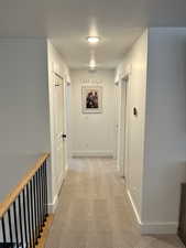 Hall featuring baseboards, a textured ceiling, and light carpet