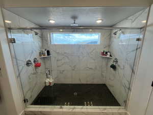 Full bathroom with healthy amount of natural light, a marble finish shower, and a textured ceiling