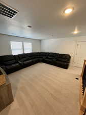 Living room with carpet, a textured ceiling, and recessed lighting