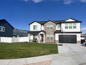 View of front facade featuring stucco siding, a garage, stone siding, and driveway