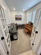 Carpeted office with french doors and recessed lighting