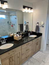 Full bath featuring marble finish flooring, double vanity, and a marble finish shower