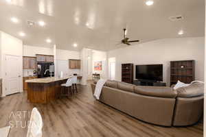 Living room featuring vaulted ceiling, a ceiling fan, and wood finished floors