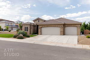 View of front of house with stucco siding, a garage, concrete driveway, a tiled roof, and stone siding