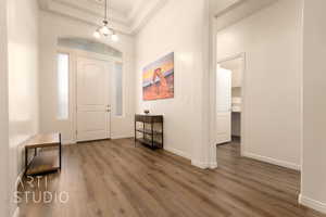 Foyer entrance featuring dark wood finished floors, a chandelier, baseboards, and a raised ceiling