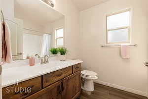 Bathroom with toilet, vanity, wood finished floors, baseboards, and a shower with shower curtain