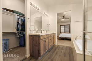 Bathroom featuring a ceiling fan, wood finished floors, double vanity, and baseboards