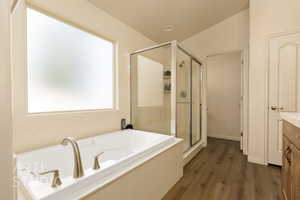 Full bathroom featuring a stall shower, a garden tub, wood finished floors, and vanity