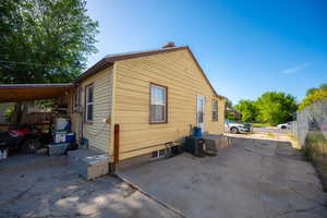 View of side of home with a chimney and central AC unit