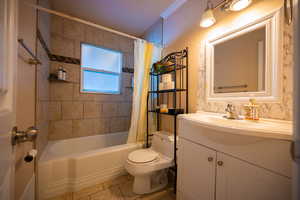 Full bath featuring toilet, vanity, shower / bath combo, and tile patterned flooring