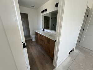 Bathroom with a stall shower, double vanity, and toilet