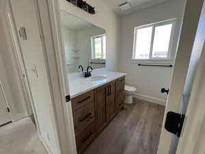 Full bath featuring vanity, toilet, wood finished floors, and a shower
