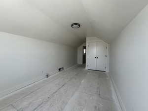 Additional living space with vaulted ceiling, a textured ceiling, and baseboards