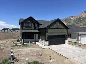 View of front of property featuring stone siding, board and batten siding, driveway, a shingled roof, and a mountain view