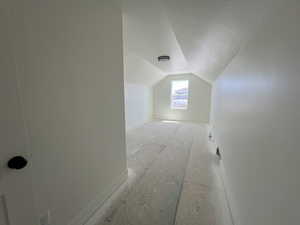 Bonus room with lofted ceiling, baseboards, and a textured ceiling