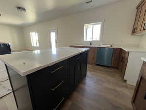 Kitchen featuring dishwasher, light wood-style flooring, a sink, and plenty of natural light