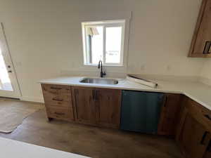Kitchen with dishwashing machine, a sink, and brown cabinets