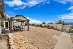 Fenced backyard featuring a gazebo, a patio, and a gate