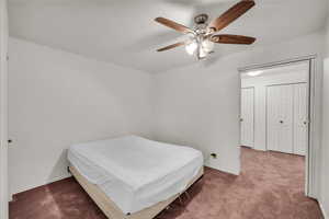 Carpeted bedroom featuring ceiling fan