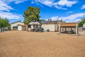 Rear view of house featuring a patio area, roof mounted solar panels, and central AC unit