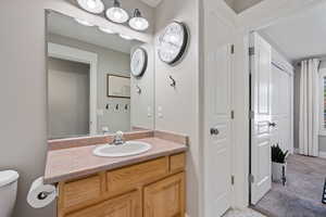Bathroom featuring vanity, toilet, and baseboards