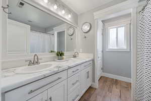 Full bathroom featuring double vanity, wood finished floors, and baseboards