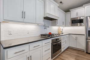 Kitchen with stainless steel appliances, white cabinetry, dark countertops, and decorative backsplash