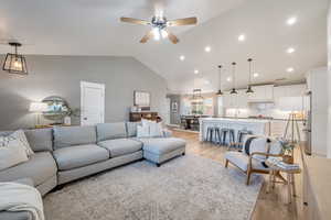 Living room featuring light wood-style floors, lofted ceiling, a ceiling fan, and recessed lighting
