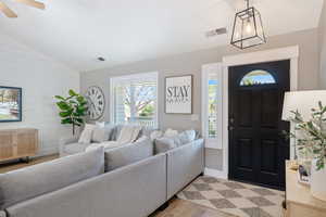 Entrance foyer with lofted ceiling, wood finished floors, ceiling fan, baseboards, and wooden walls