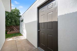 View of exterior entry featuring stucco siding and a patio area