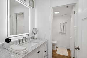 Bathroom with vanity, toilet, and wood finished floors
