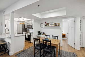 Dining room featuring light wood-style flooring, a raised ceiling, and baseboards