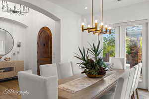 Dining area with a chandelier, wood finished floors, arched walkways, and recessed lighting