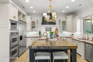 Kitchen with appliances with stainless steel finishes, a sink, an island with sink, decorative backsplash, and recessed lighting
