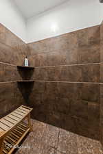 Bathroom with stone finish floors and tiled shower