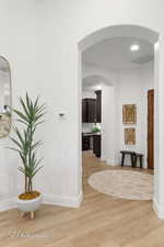 Hallway featuring light wood-type flooring, baseboards, and arched walkways