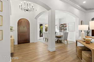 Entrance foyer with a chandelier, light wood finished floors, recessed lighting, arched walkways, and baseboards