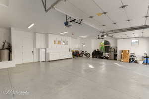 Garage featuring a garage door opener, freestanding refrigerator, and water heater