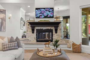 Living area featuring wood finished floors, a stone fireplace, and recessed lighting
