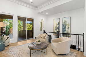 Living area with wood finished floors, an upstairs landing, recessed lighting, and ornamental molding