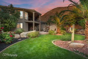 Rear view of property featuring a balcony, stucco siding, a yard, a patio area, and a mountain view