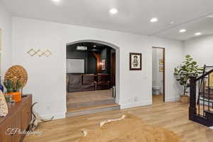 Corridor featuring arched walkways, stairway, wood finished floors, recessed lighting, and baseboards