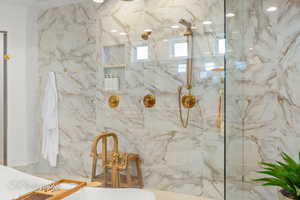 Full bath featuring a soaking tub and a marble finish shower