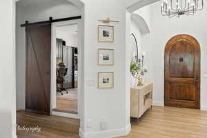 Entryway featuring wood finished floors, a chandelier, baseboards, and arched walkways