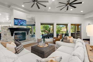 Living room featuring a ceiling fan, ornamental molding, a fireplace, recessed lighting, and wood finished floors