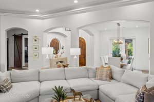 Living area with a chandelier, recessed lighting, arched walkways, and a barn door