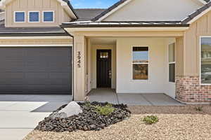 View of front of home with board and batten siding, brick siding, a garage, and driveway