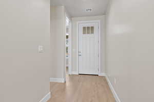 Doorway to outside featuring baseboards and light wood-style flooring