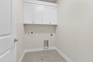 Washroom with hookup for an electric dryer, cabinet space, baseboards, and light tile patterned floors