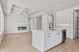 Kitchen with a sink, stainless steel dishwasher, coffered ceiling, recessed lighting, and light wood finished floors
